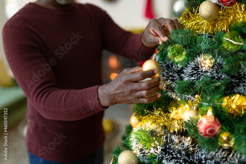 Midsection of african american senior man decorating christmas tree