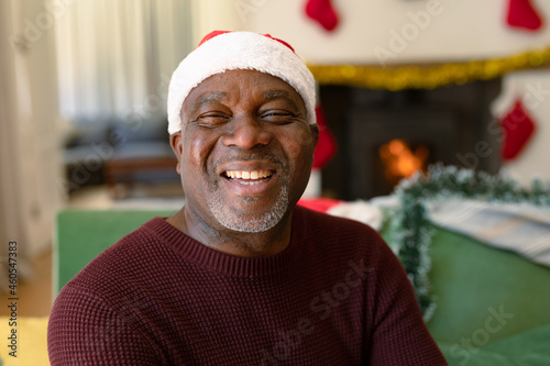 Happy african american senior man in santa hat looking at camera at christmas time