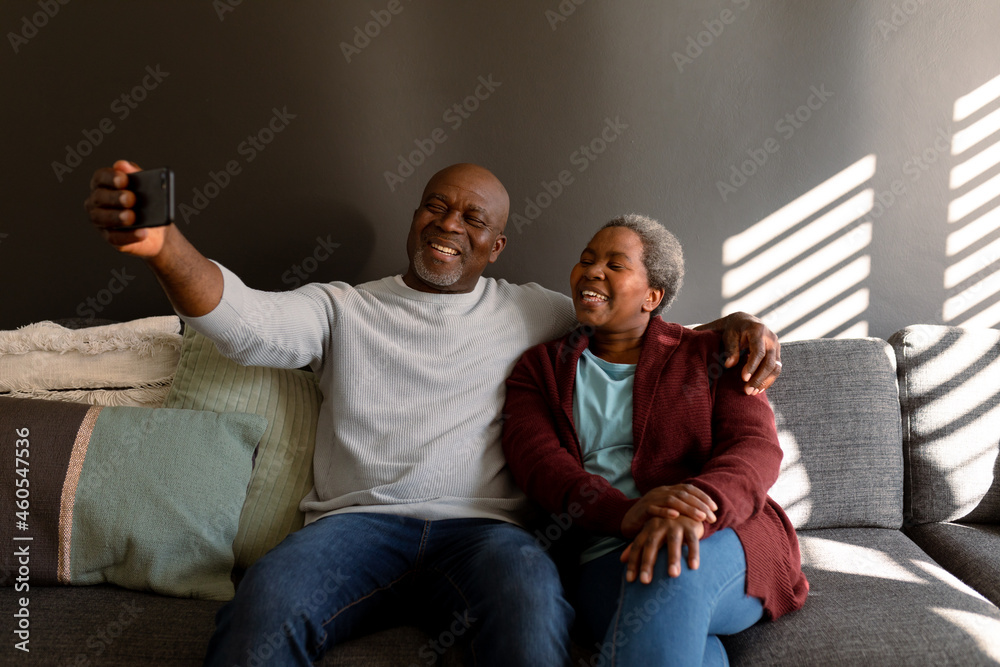 Happy african american senior couple taking selfie at home