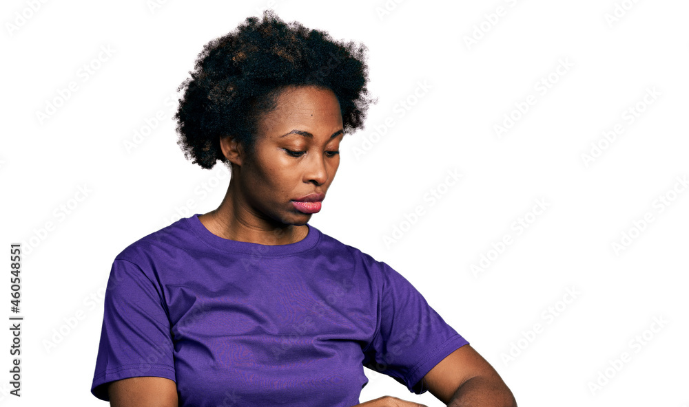 African american woman with afro hair wearing casual purple t shirt checking the time on wrist watch, relaxed and confident African american woman with afro hair wearing casual purple t shirt checking the time on wrist watch, relaxed and confident