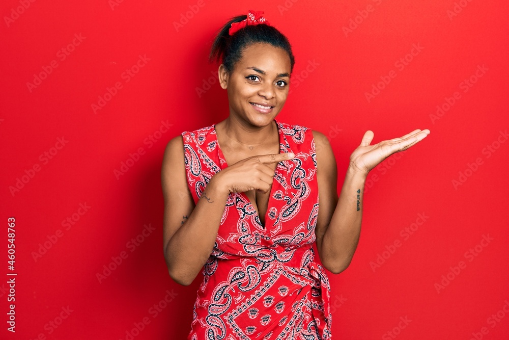 Young african american girl wearing casual clothes amazed and smiling to the camera while presenting with hand and pointing with finger. Young african american girl wearing casual clothes amazed and smiling to the camera while presenting with hand and pointing with finger.