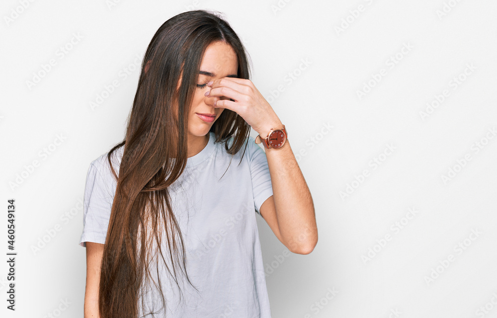 Young hispanic girl wearing casual white t shirt tired rubbing nose and eyes feeling fatigue and headache. stress and frustration concept. Young hispanic girl wearing casual white t shirt tired rubbing nose and eyes feeling fatigue and headache. stress and frustration concept.