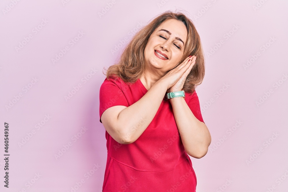 Middle age caucasian woman wearing casual clothes sleeping tired dreaming and posing with hands together while smiling with closed eyes. Middle age caucasian woman wearing casual clothes sleeping tired dreaming and posing with hands together while smiling with closed eyes.
