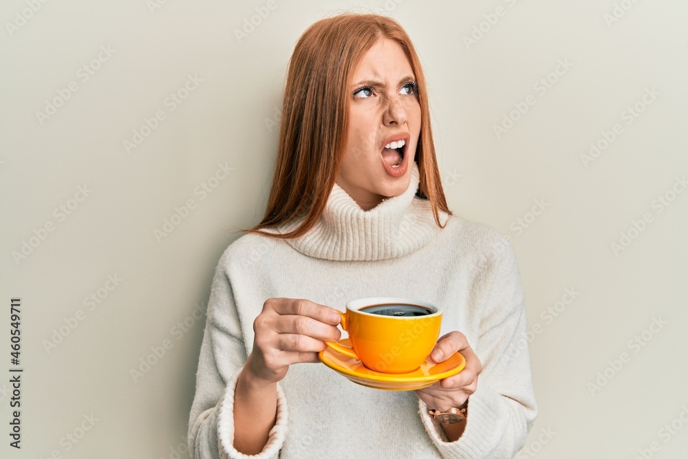 Young irish woman drinking a cup of coffee angry and mad screaming frustrated and furious, shouting with anger. rage and aggressive concept. Young irish woman drinking a cup of coffee angry and mad screaming frustrated and furious, shouting with anger. rage and aggressive concept.