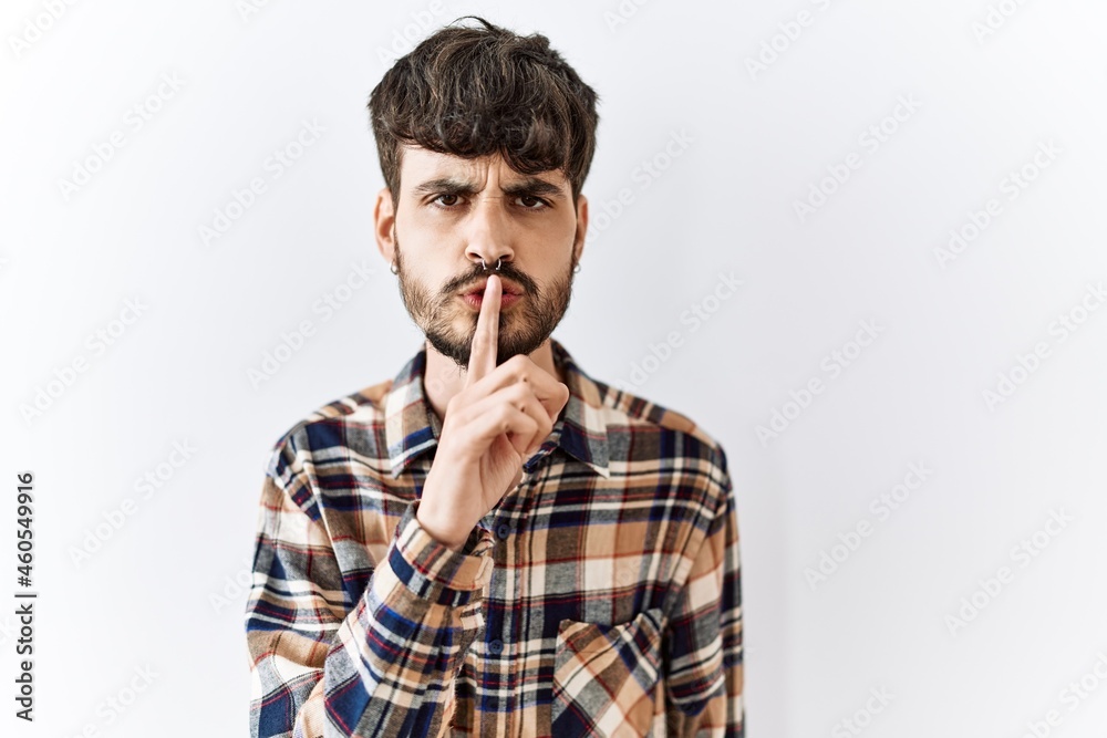 Hispanic man with beard standing over isolated background asking to be quiet with finger on lips. silence and secret concept. Hispanic man with beard standing over isolated background asking to be quiet with finger on lips. silence and secret concept.