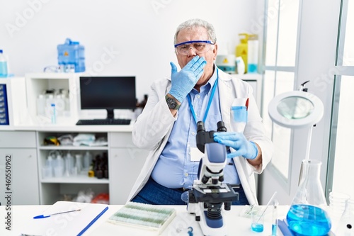 Senior caucasian man working at scientist laboratory bored yawning tired covering mouth with hand. restless and sleepiness.