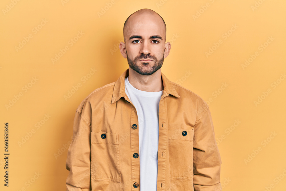 Young bald man wearing casual clothes with serious expression on face. simple and natural looking at the camera. Young bald man wearing casual clothes with serious expression on face. simple and natural looking at the camera.