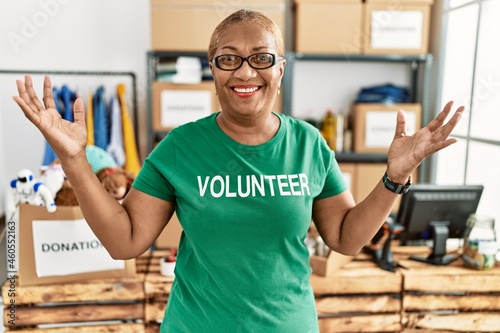 Cuadro en lienzo Mature hispanic woman wearing volunteer t shirt at donations stand celebrating v