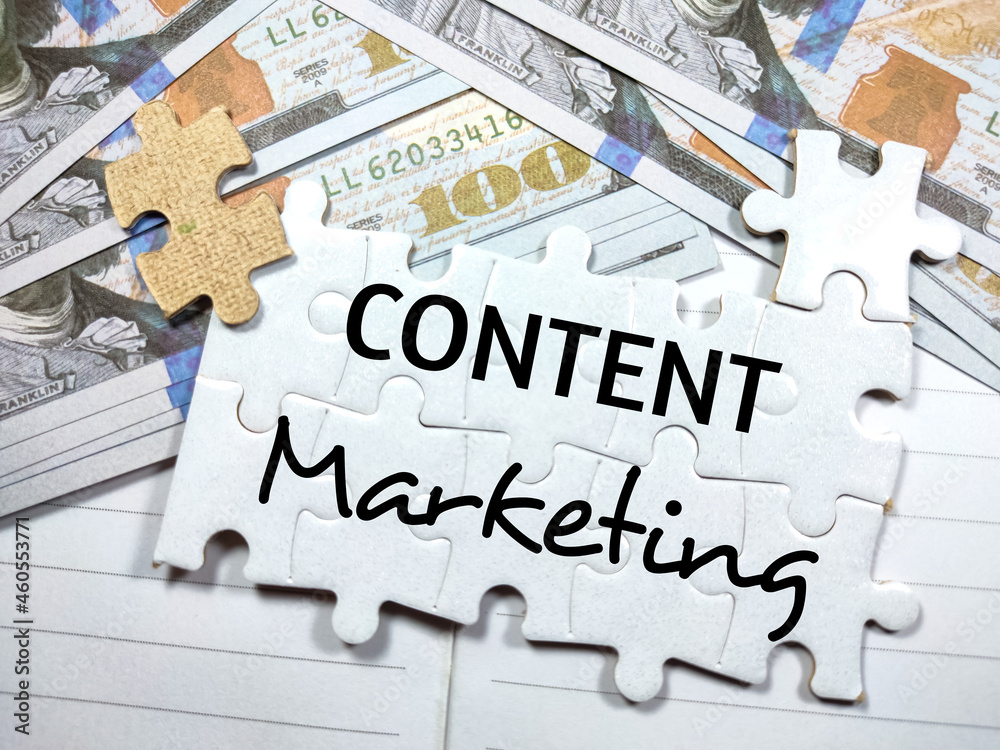 White jigsaw puzzle written with text CONTENT Marketing with dollar money on a notebook. White jigsaw puzzle written with text CONTENT Marketing with dollar money on a notebook.