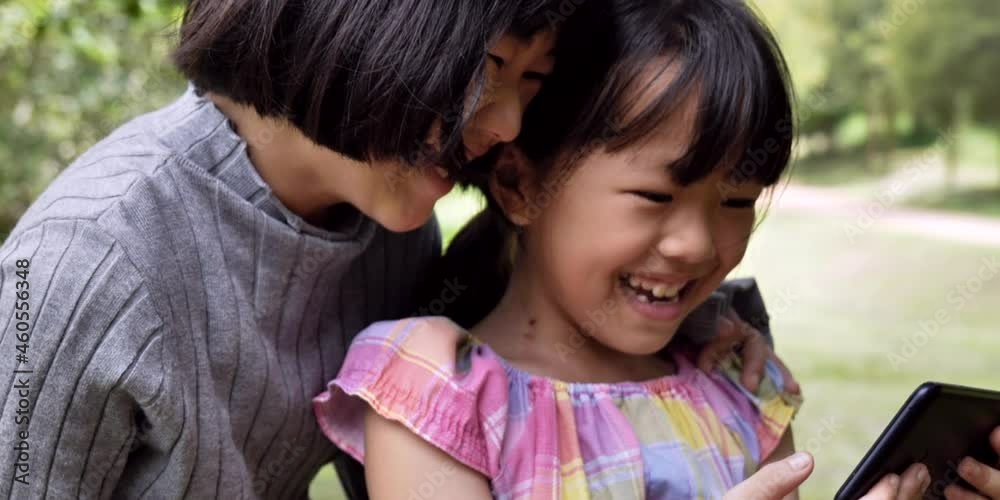Two sister asian happy video chat using smartphone in park outdoor. 4k footage slow motion. Two sister asian happy video chat using smartphone in park outdoor. 4k footage slow motion.