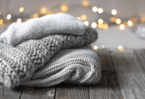 Fototapeta Naklejka Na Ścianę i Meble -  Cozy winter background with a stack of knitted sweaters and lights, copy space.