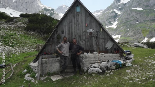 Portrait of two serious mountain men in front of cabbin close up wide handheld photo