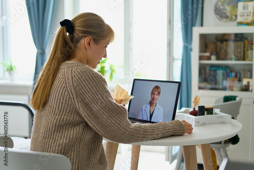 Woman calling doctor online. Telemedicine concept. Future teleconsulting. Diagnostic from home. Videoconference with therapist in kitchen. Sick female asking for help. E-medicine photo