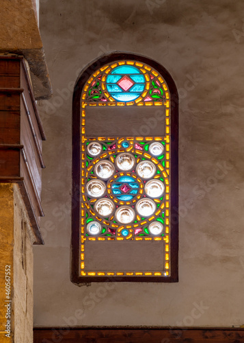 Perforated stucco window decorated with colorful stain glass with geometrical circular patterns, located at Mamluk era public historical Beshtak Palace,, Moez Street, Cairo, Egypt photo