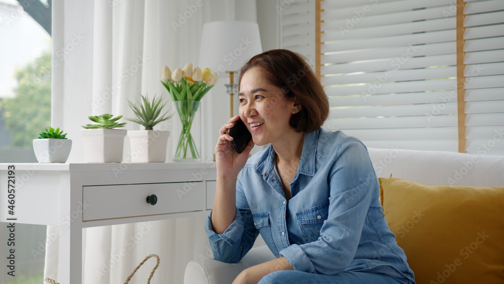 Asia elder lady people, latin mom sitting at home cozy sofa couch use digital 5G cellular cellphone on wifi wireless service support in remotely social distance call to advice, gossip, order online.