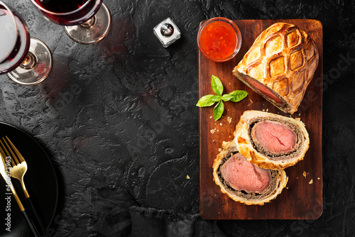 Beef Wellington - beef tenderloin festive dish. English cuisine. Black stone background. top view photo