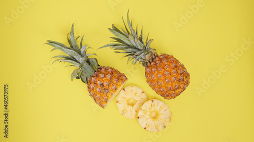 pineapple fruit and some of its pieces isolated on a yellow background