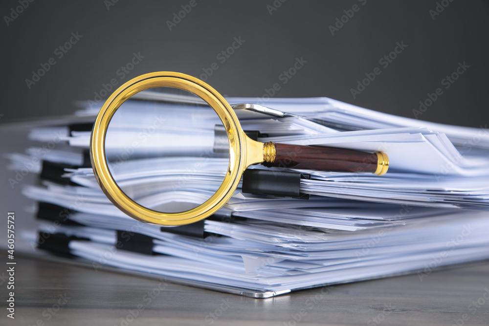 Fotografie Stack of documents and magnifying glass on the table.