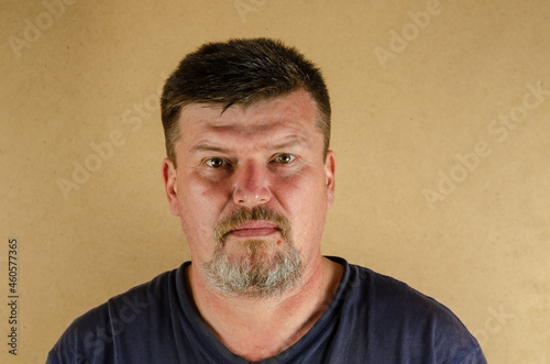 Portrait of a 45-year-old man looking at the camera. Adult unshaven male indoors.