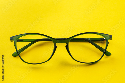 Stylish eyeglasses over yellow background. Optical store, glasses selection, eye test, vision examination at optician, fashion accessories concept.