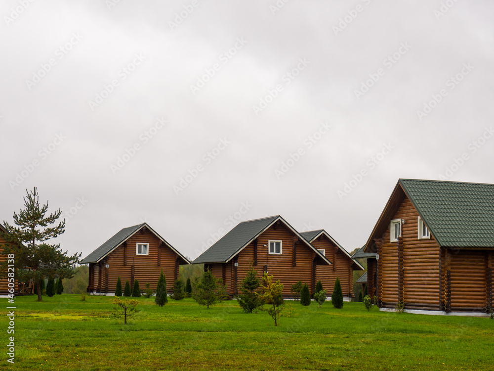 many identical Large log houses outside with a grass-covered backyard many identical Large log houses outside with a grass-covered backyard