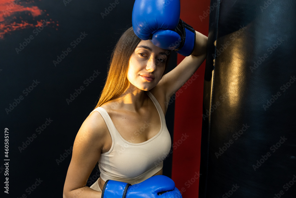 Portrait of a girl fighter in gloves near a punching bag