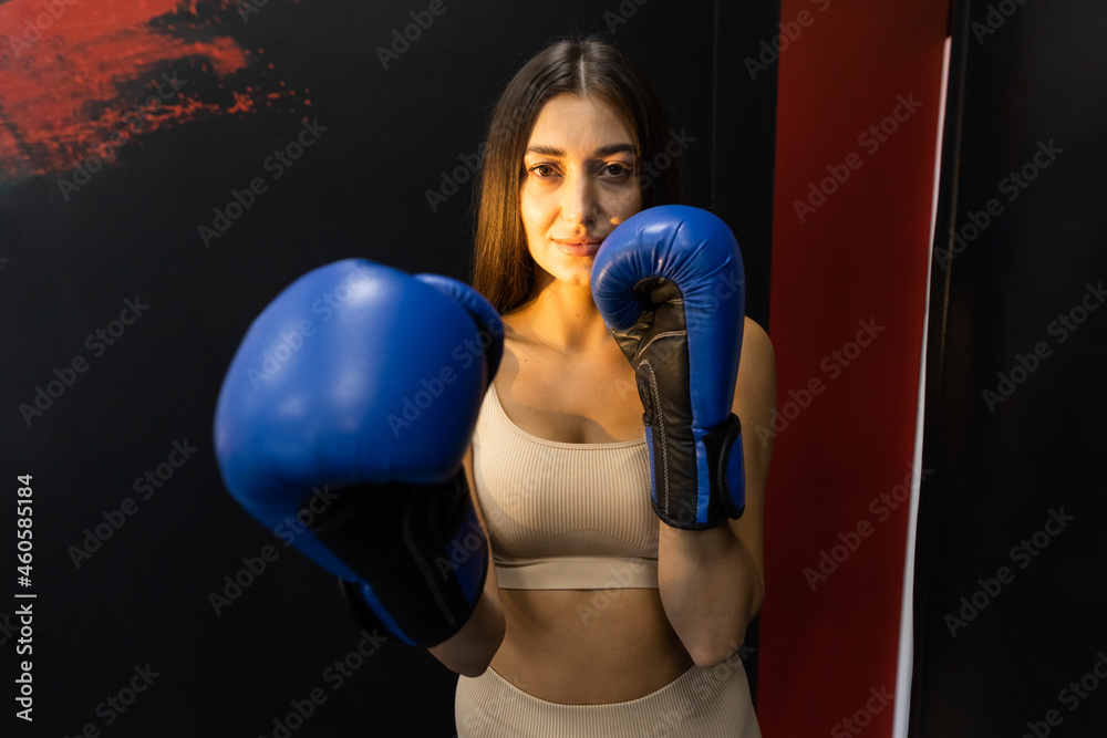 Athletic girl in blue boxing gloves posing