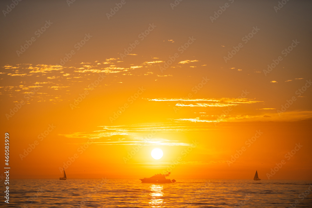 Calm golden sea with sunset sky and sun through the clouds over. Ocean and sky background, seascape.