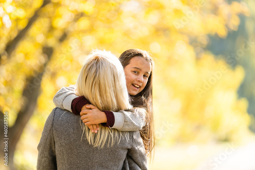Little girl and her mother enjoy sunny weather in the autumn park