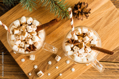 top view of a traditional chocolate Christmas drink with marshmallows in glass cropped on a wooden background.