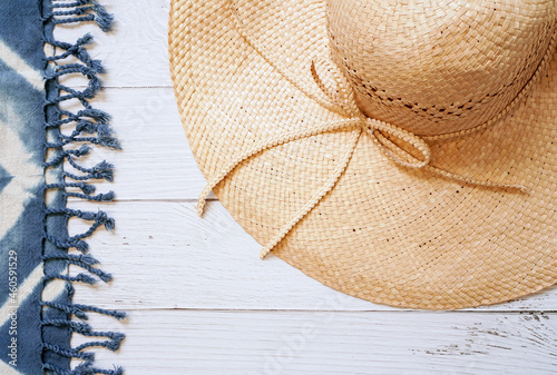 Fotografi brown floppy straw hat for lady with blue tie dye beach shawl on white wooden ba