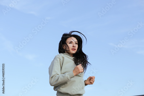 A woman in sweatshirts runs in the morning workout