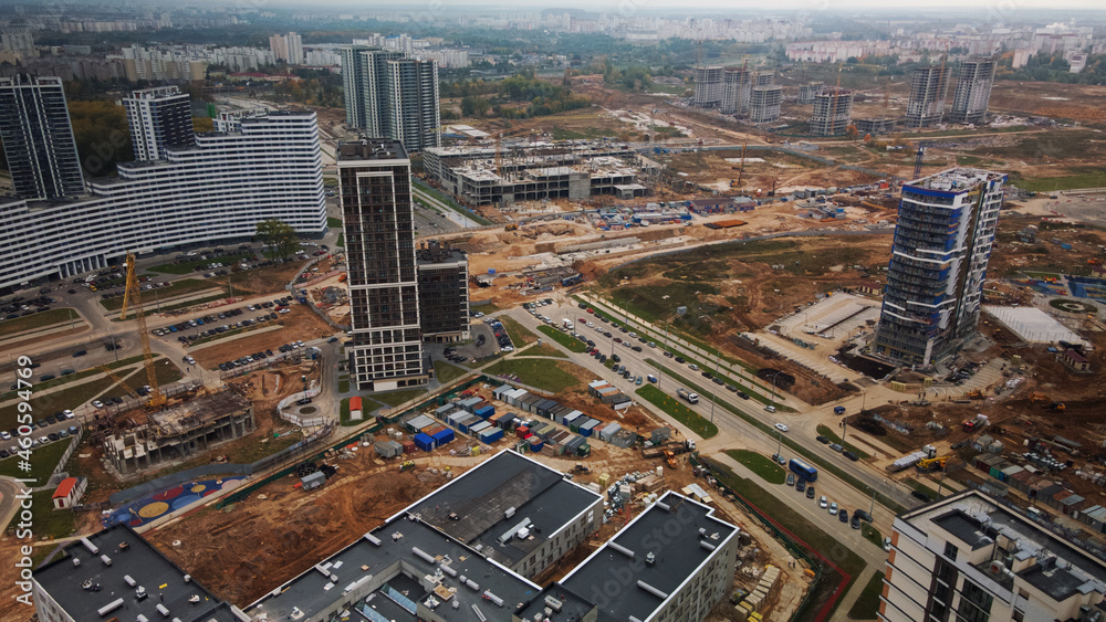 Construction of modern multi-storey buildings. Construction of a new city block. Buildings under construction and tower cranes. Aerial photography in cloudy weather.