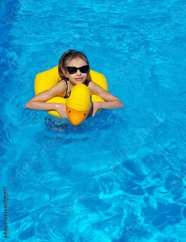 Cute girl swimming in pool with a yellow rubber duck