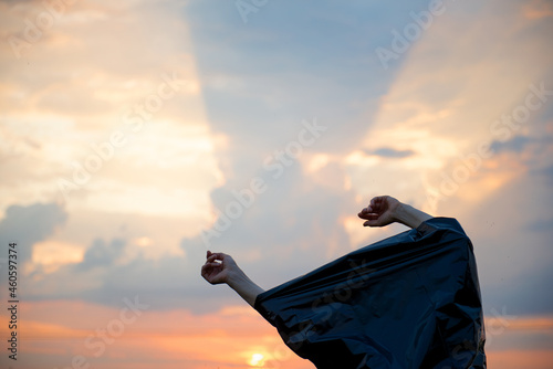 Women's hands in a black plastic bag on a sunset sky background © Zelma