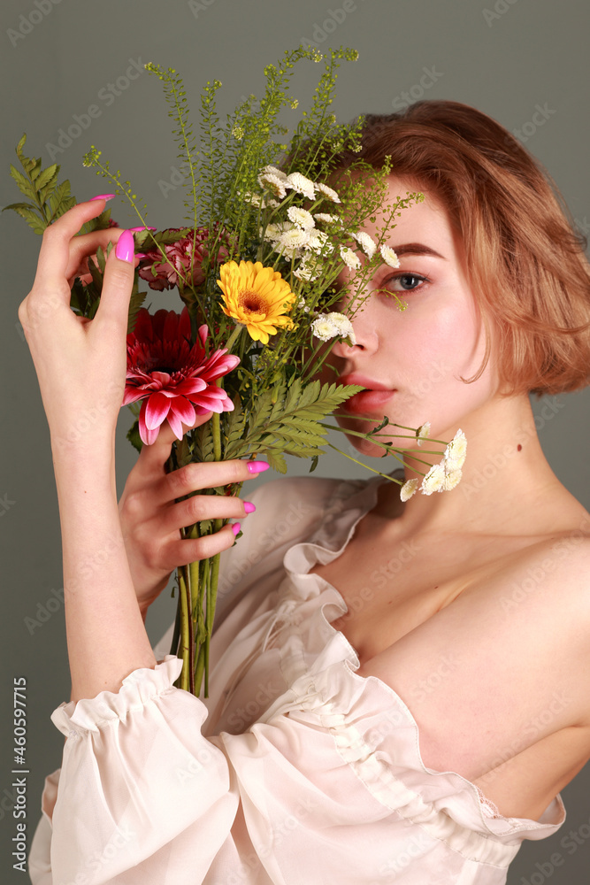 Girl with naked shoulders with an unusual bouquet of beautiful flowers