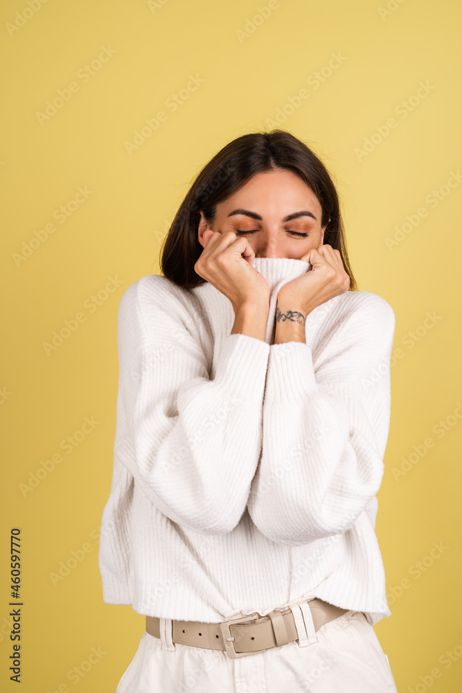 Young woman in white warm sweater cute warm herself pulling sweater on face