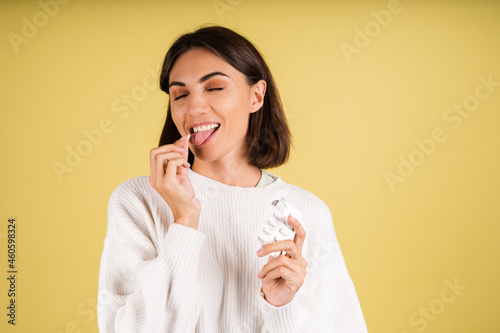 Young woman in white warm sweater taking pill happy smiling health self care