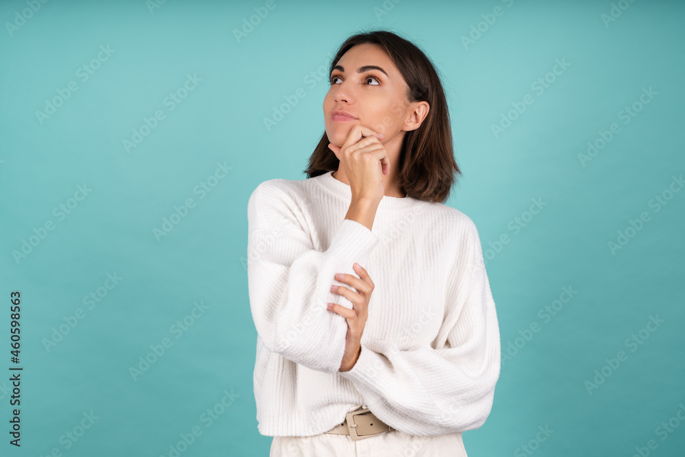 Young woman in white warm sweater happy thoughtful look left with smile Young woman in white warm sweater happy thoughtful look left with smile