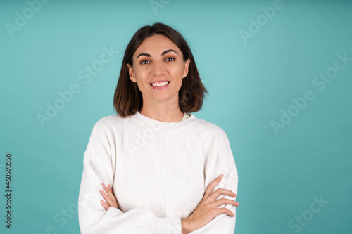 Young woman in white warm sweater happy smiling cheerful look to camera with arms crossed