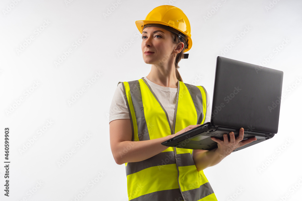 An architect in white uniform. Architect builder with laptop in his hands. Architect in yellow uniform. Girl in construction uniform. Portrait of woman engineer. Concept - construction software An architect in white uniform. Architect builder with laptop in his hands. Architect in yellow uniform. Girl in construction uniform. Portrait of woman engineer. Concept - construction software
