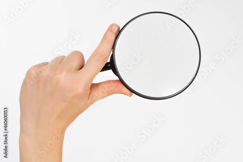 Magnifying glass. Magnifier with copy space. Female hand with a magnifying glass. Place for text under a magnifying glass. Concept - careful study or research. Magnifier on a white background.