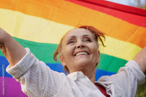 Фотография Beautiful mature senior woman with charming smile holding rainbow LGBT flag in h