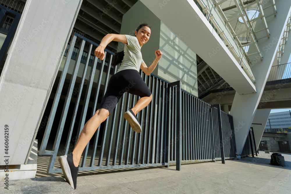Φωτογραφία Graceful sportive Asian woman in stylish tracksuit jumping upward moment at trai
