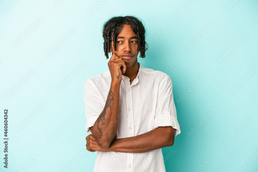 Young african american man isolated on blue background confused, feels doubtful and unsure. Young african american man isolated on blue background confused, feels doubtful and unsure.