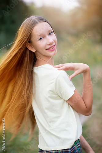 Fototapeta Naklejka Na Ścianę i Meble -  Beautiful teenager girl with long flowing hair on a background of green nature.