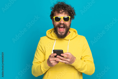 happy young man holding phone, reading news and laughing