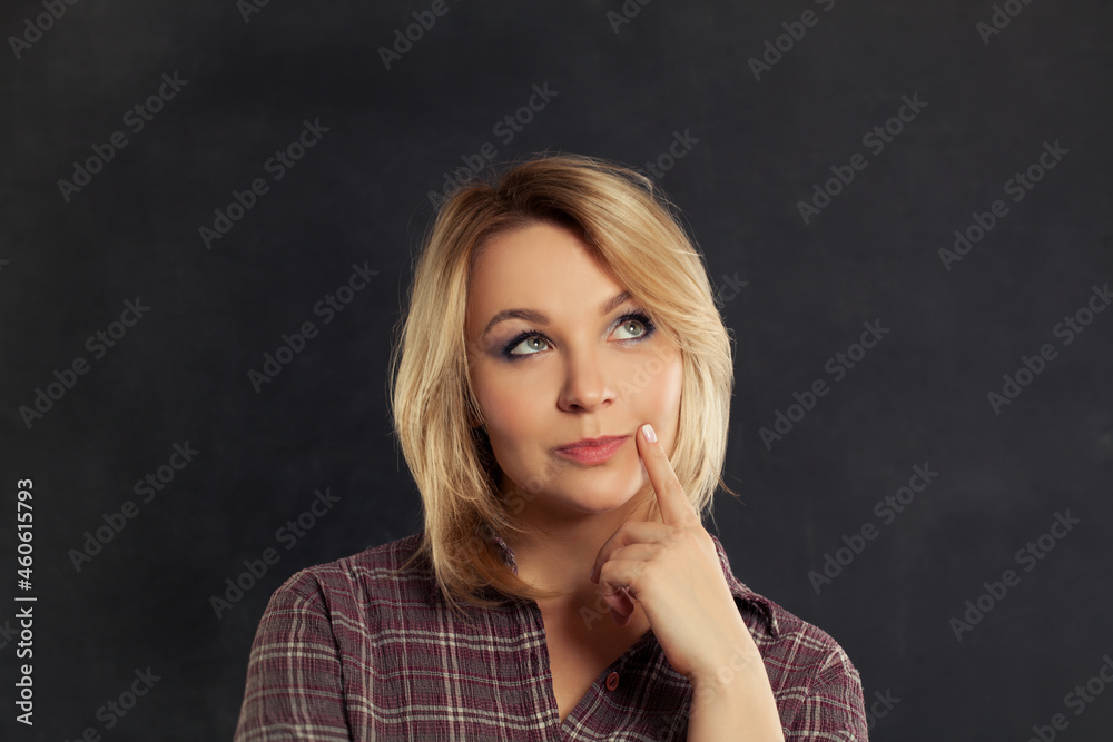 Beautiful young woman thinking and looking upwards on black background Beautiful young woman thinking and looking upwards on black background
