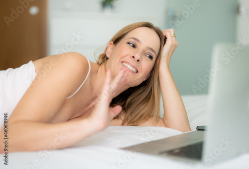 Attractive caucasian woman sitting on bed at home working on the computer
