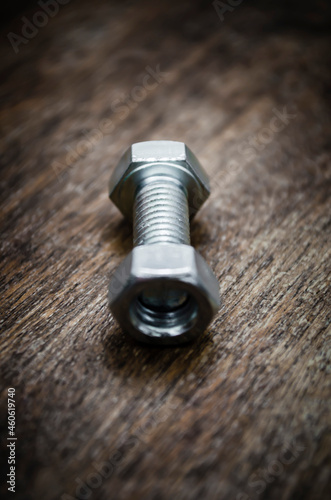 Metal bolt and nut on old wooden background stylized blur background